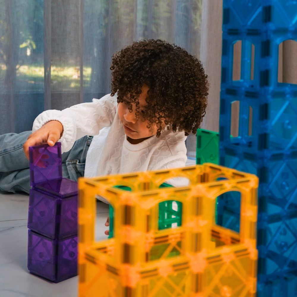Meisje speelt met paarse magnetische tegels